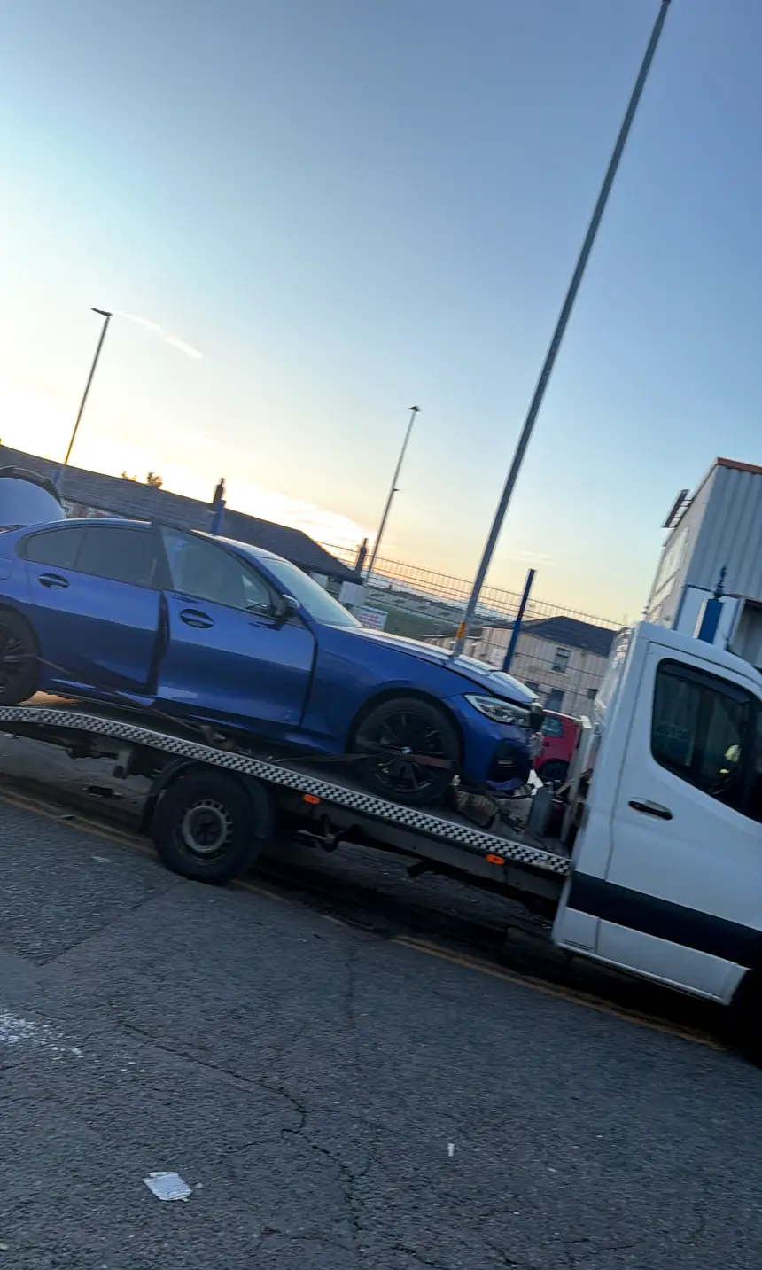 A&J's white flatbed carrying a blue BMW 3 Series at dusk